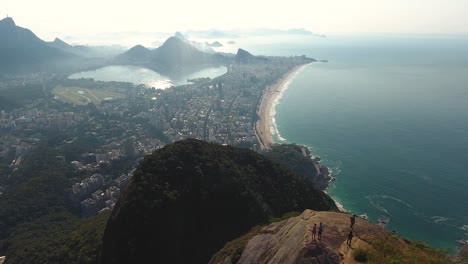 overhead aerial drone shot over a mountain top revealing two young adults admiring the view