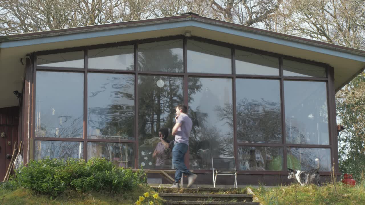 Man jumps in excitement receiving good news on phonecall beside cabin