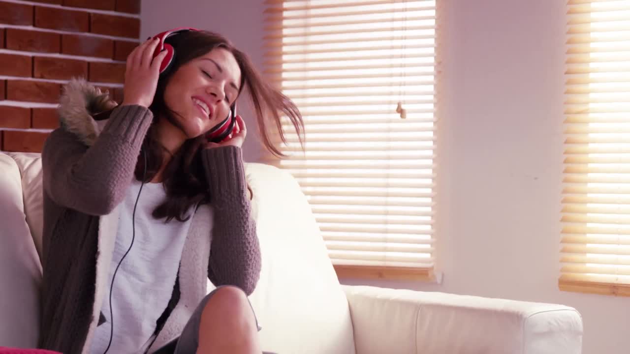 미소 짓는 여자 가 헤드폰 으로 음악 을 듣고 있다
