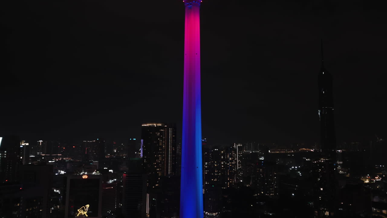 Aerial view tilting toward the illuminated Kuala Lumpur tower, night in Malaysia