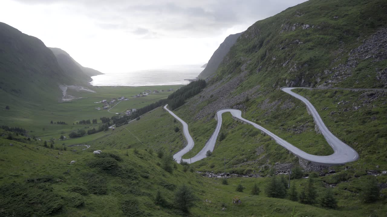 величественная извилистая дорога, ведущая к пляжу для серфинга ходдевик в норвегии, вид с рук