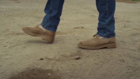 botas de gamuza, piernas en primer plano, dueño de un negocio caminando por un camino de campo.