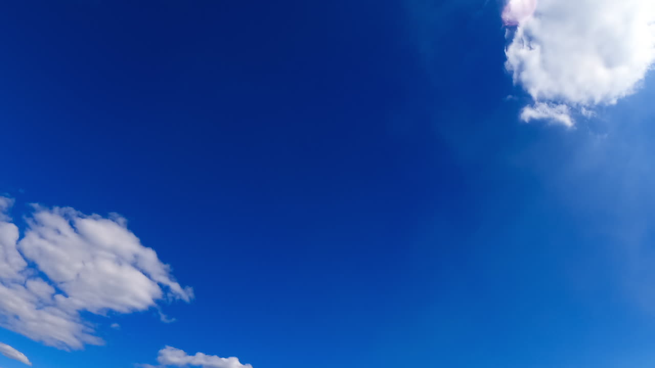 Beautiful azure sky in summer from low angle view. Fluffy white clouds transform in the atmosphere. Timelapse