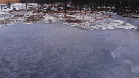 Drone-Over-Frozen-Icy-Winter-Pond-In-Forest