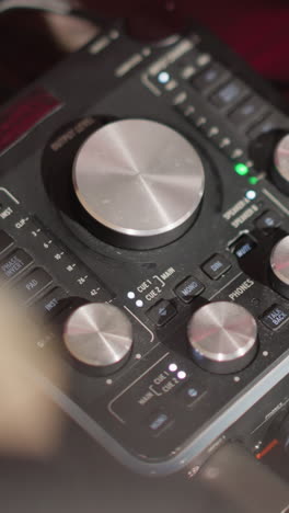 close-up shot of a sound mixer on a table in a recording studio, featuring various knobs and dials for controlling audio levels