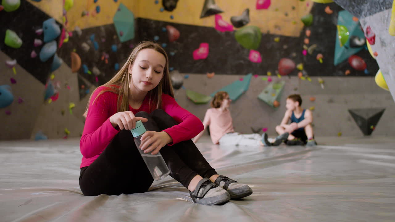 십대 소녀 가 등반 체육관 에서 물 을 마시고 있다