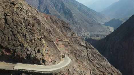 Drone-shot-of-vehicle-on-Fairy-Meadows-Road-in-Pakistan,-second-deadliest-highway-in-the-world,-rotating-aerial