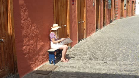 Hermosa-Rubia-Descansando-En-Un-Banco-Y-Leyendo-En-La-Ciudad-De-Puerto-De-La-Cruz