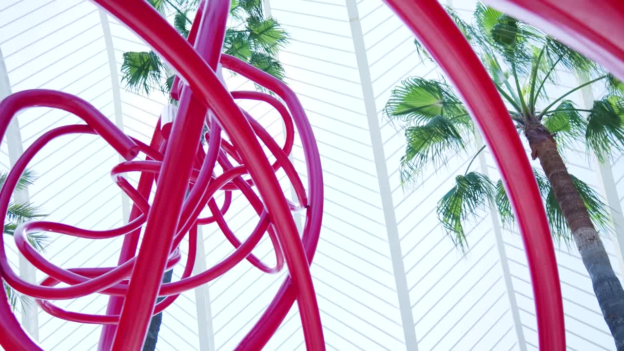 Red Metal Sculpture in an Atrium with Palm Trees