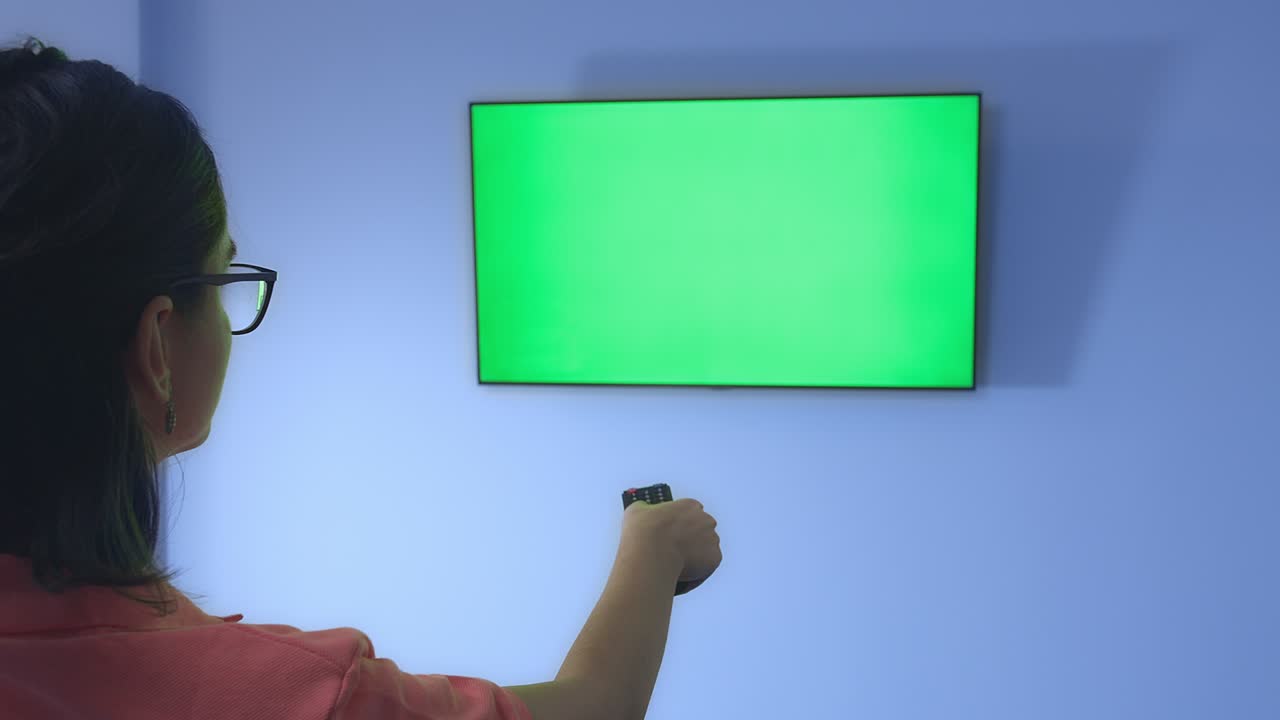 리모컨을 가진 안경을 입은 소녀가 tv 채널을 전환하고 뉴스를 보고, 크롬케이, 뒷면을 보고