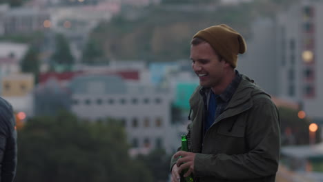 Amigos-Felices-Bailando-En-La-Azotea-Divirtiéndose-Disfrutando-Pasando-El-Rato-Al-Atardecer-Bebiendo-Cerveza-Refrescante-Compartiendo-Vistas-Del-Horizonte-De-La-Ciudad