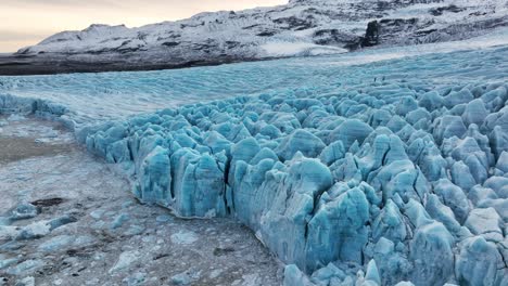 aerial landscape view over textured ice formations of a glacier in iceland, at sunset