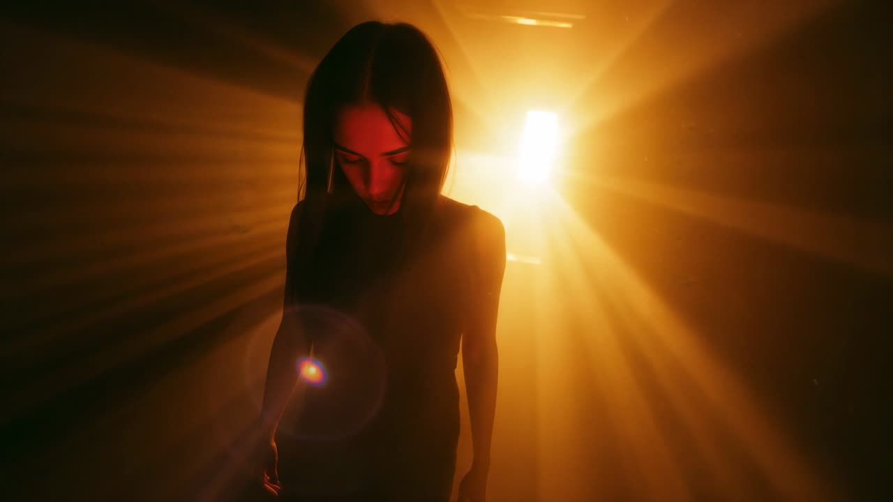 Walking woman, dark dress, from lit doorway into dim hallway, light drawing her amid lens flare