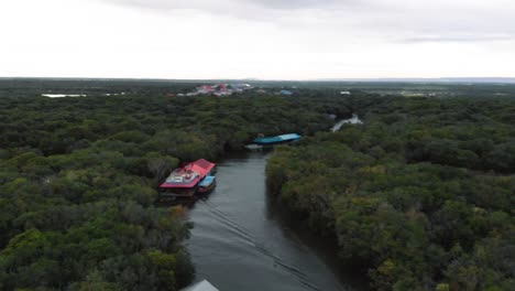 an aerial drone shot over a partially submerged forest in cambodia, with small boats navigating through the trees, showcasing the region's unique seasonal flooding and natural beauty.