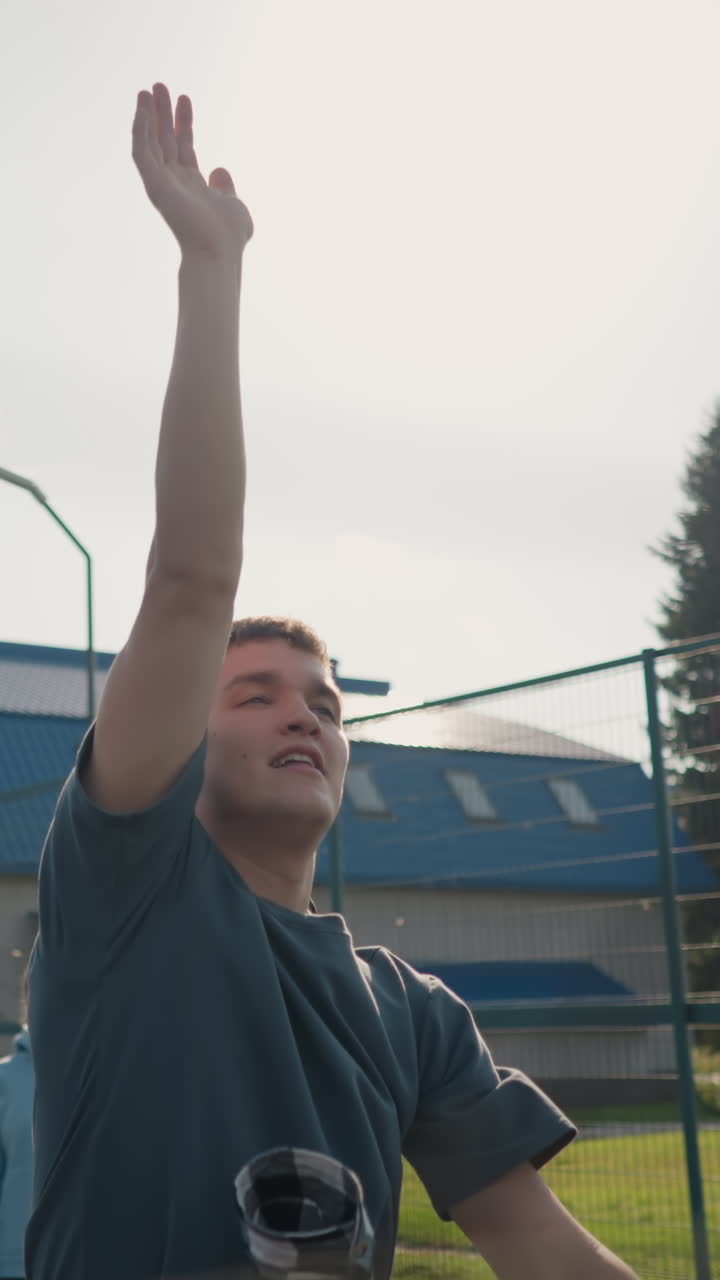 jugador de voleibol sirve la pelota a la dama en la sesión de entrenamiento, que lo golpea de vuelta, salta para un golpe, con vista borrosa de otros jugadores en el fondo en la cancha al aire libre