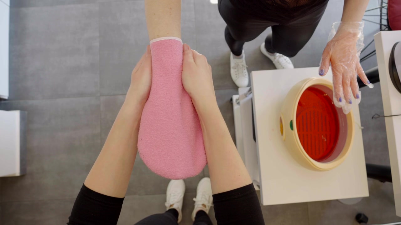 Beauty salon, a cosmetologist puts a glove on the client's hand after removing it from the paraffin