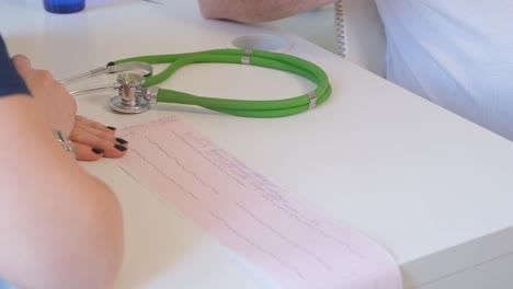 a woman doctor is holding a cardiogram for further examination of a sick man in a modern clinic. the latest technologies in medicine.
