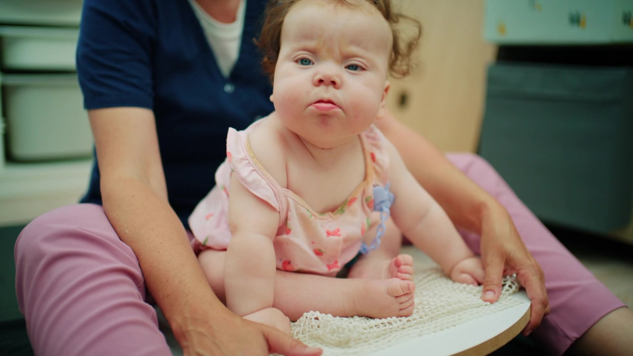 Bambino con sindrome di Down che esegue esercizi di equilibrio durante la terapia fisica di intervento precoce con un terapista.