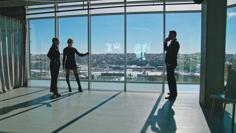business people on office windows background. businessman talking the phone while standing in front of two beautiful female partners