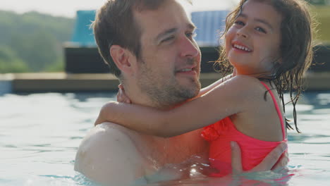 father and daughter having fun in swimming pool on summer vacation together