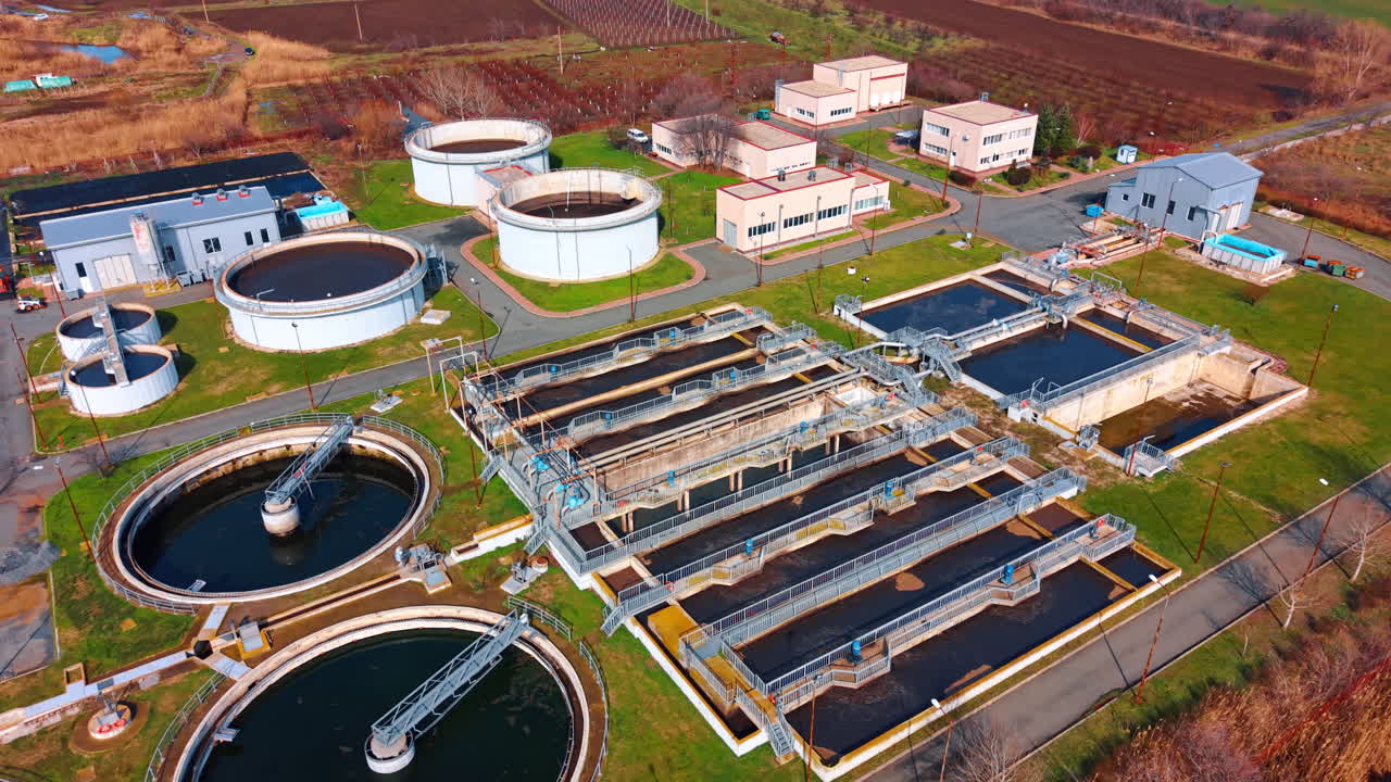 High angle view of wastewater processing basins and tanks. Oblique aerial shot of a functioning sewage treatment plant with infrastructure