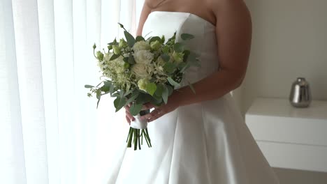 bride holding a bouquet of white and green flowers in an elegant strapless dress