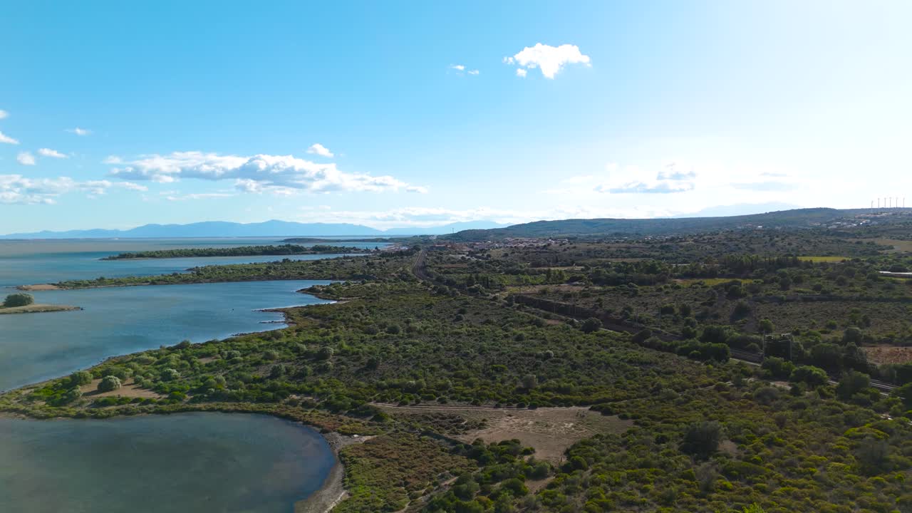 프랑스 남부의 garrigue의 드론 공중 촬영, 낮은 식물과 왼쪽에 바다, 중간에 철도 노선, 배경에 산, 몇 개의  구름과 함께 파란 하늘