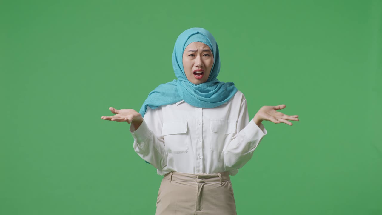 Wondering Asian Muslim Woman Saying Why And Standing Doubtfully In The Green Screen Background Studio