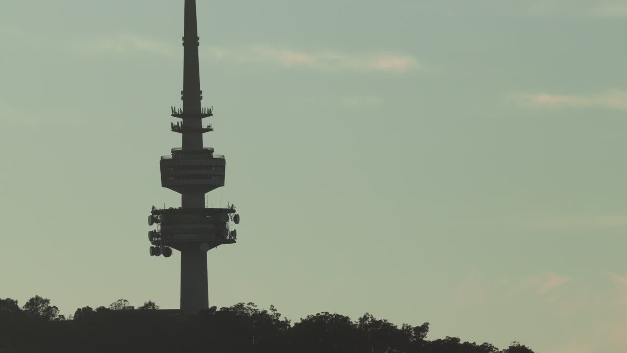 A detailed close view of the silhouetted Canberra Tower set against a soft blue sky at first light