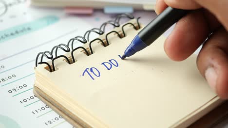 close up of person writing 'to do list' in notebook