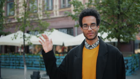 man waving hello outside cafe