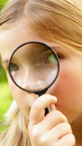 cute little girl using magnifying glass in park