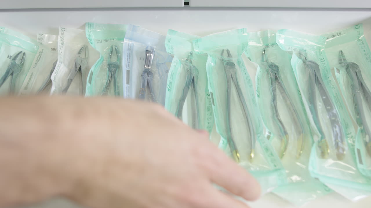 Opening up drawer in dentist's office to remove forceps in sterile wrapper