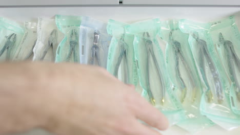 opening up drawer in dentist's office to remove forceps in sterile wrapper