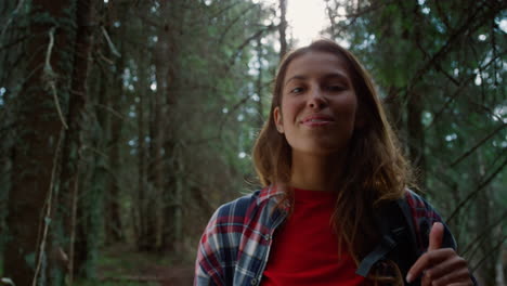 joyful woman posing at camera in woods. female hiker showing thumbs up sign