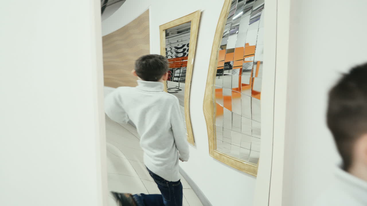 Boy playing with distorted mirror in museum of science