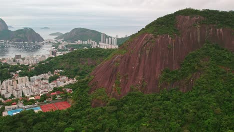 Fly-over-Rio-de-Janerio-with-its-flat-stone-hills,-clay-tennis-courts-and-cloudy-day-Brazilian-architecture