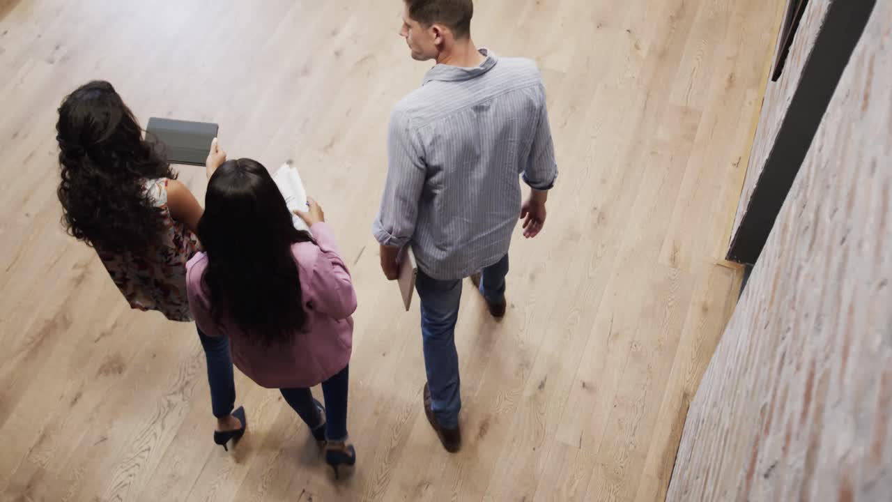High angle view of diverse male and female colleagues in discussion using tablet in office foyer