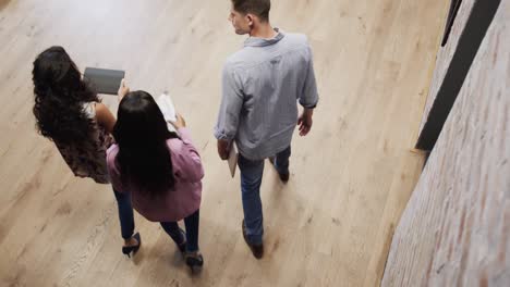 High-angle-view-of-diverse-male-and-female-colleagues-in-discussion-using-tablet-in-office-foyer