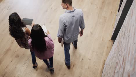 vista de alto ángulo de diversos colegas masculinos y femeninos en discusión usando tableta en el vestíbulo de la oficina