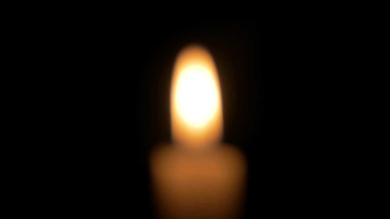 Single warn golden candle burning out of focus