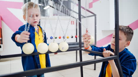 two brothers are experimenting with newton's pendulum. the concept of physics. museum of science