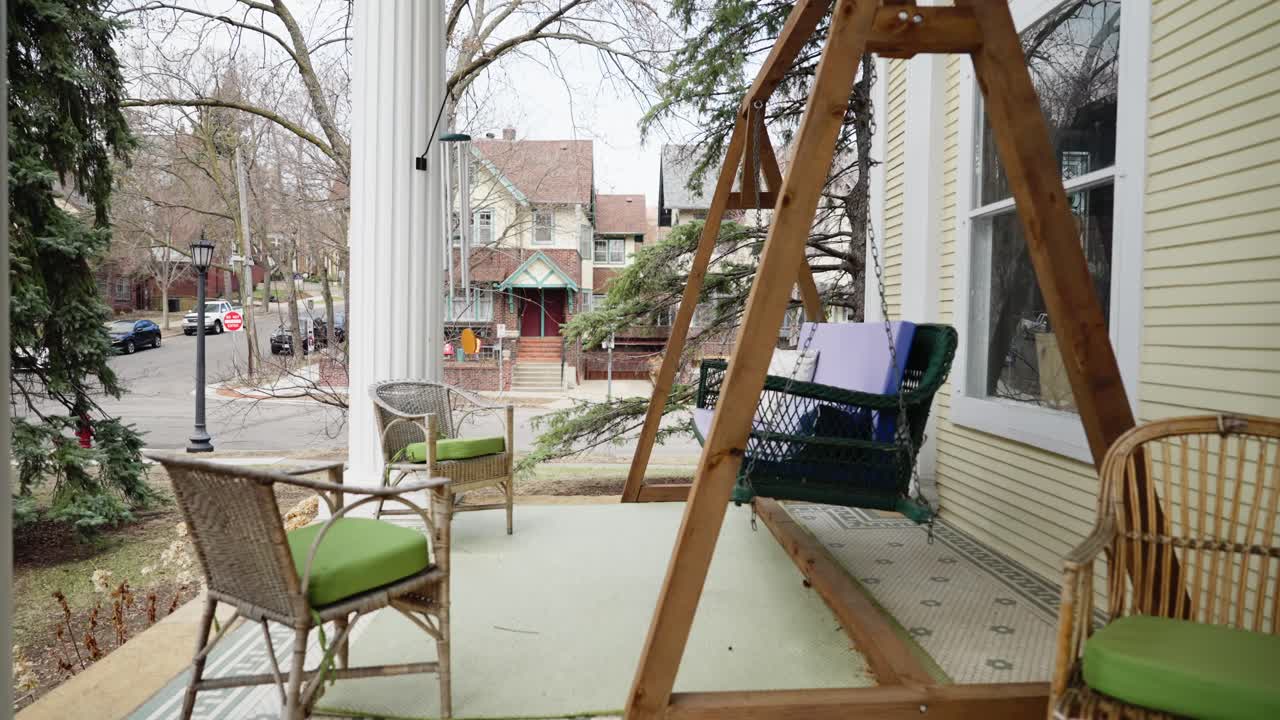 Charming front porch with wicker chairs and a hanging swing framed by tall white columns