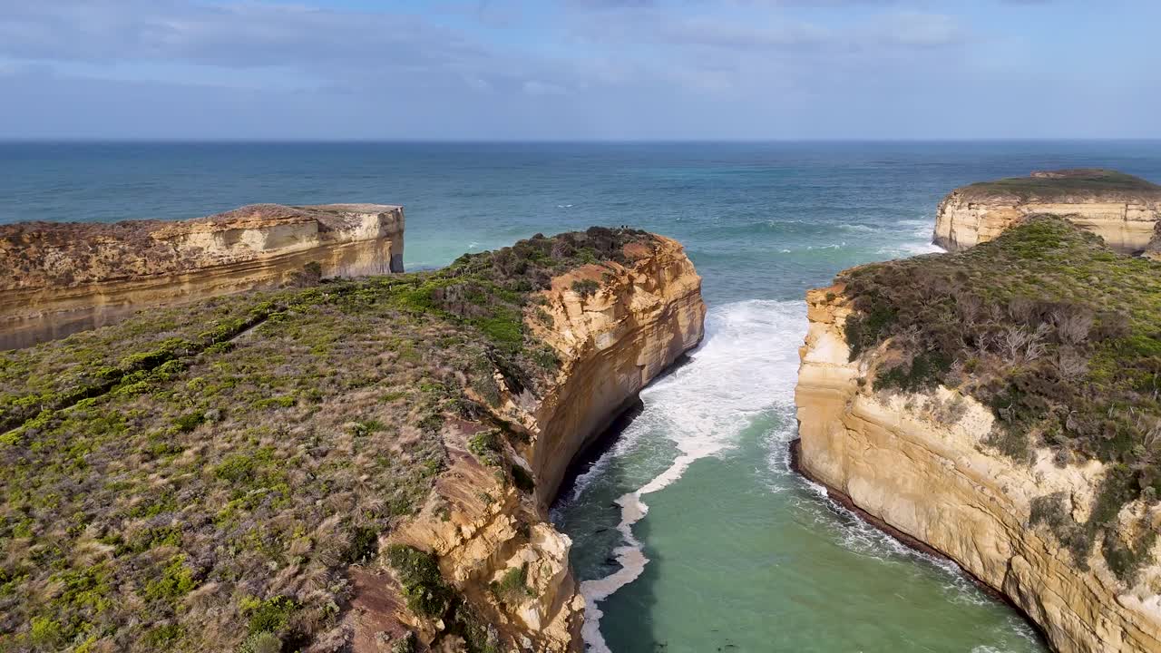 Aerial footage captures the rugged cliffs and turquoise waters of Loch Ard Gorge under clear skies, showcasing natural beauty and dramatic landscapes