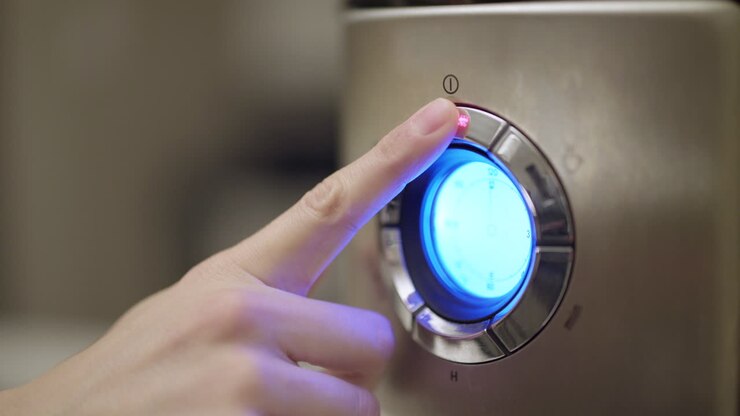 Woman's hand pressing "On" button on a coffee maker with an LED display