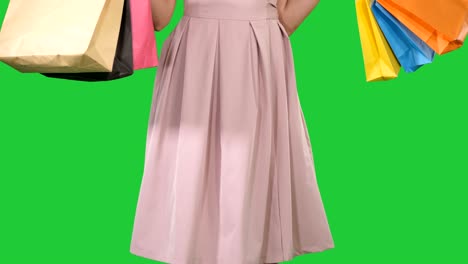 woman holding shopping bags in her hands and making a turn on a green screen, chroma key