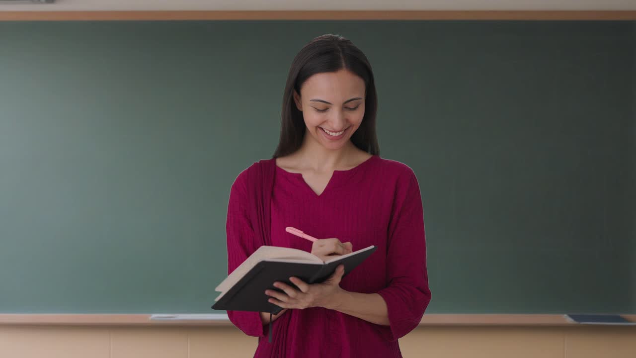 feliz maestra india tomando asistencia en la escuela