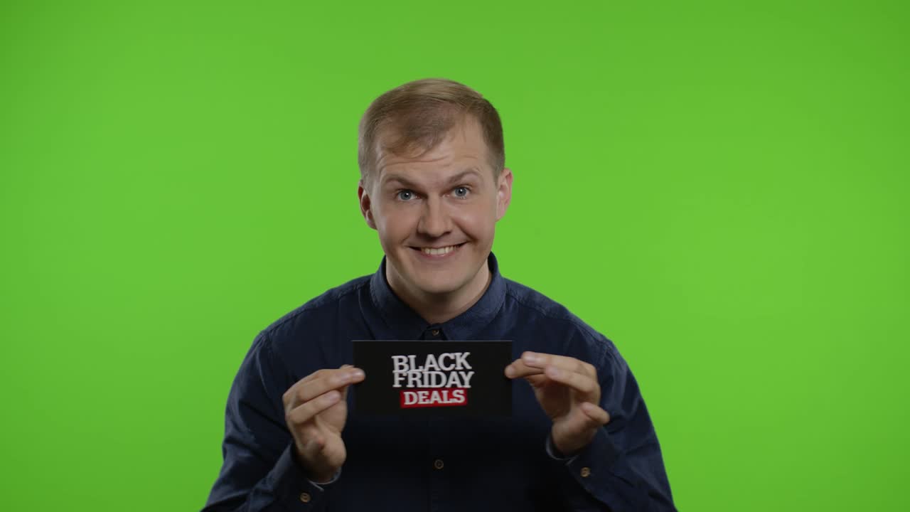 행복한 남자가 미소 짓고, 춤을 추고, 블랙 프라이데이 거래를 보여주고, 기하고, 좋은 할인을 즐기고 있습니다.