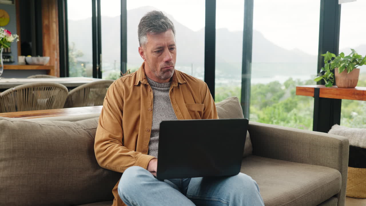Man Working on Laptop from Couch in Modern Home with Scenic View