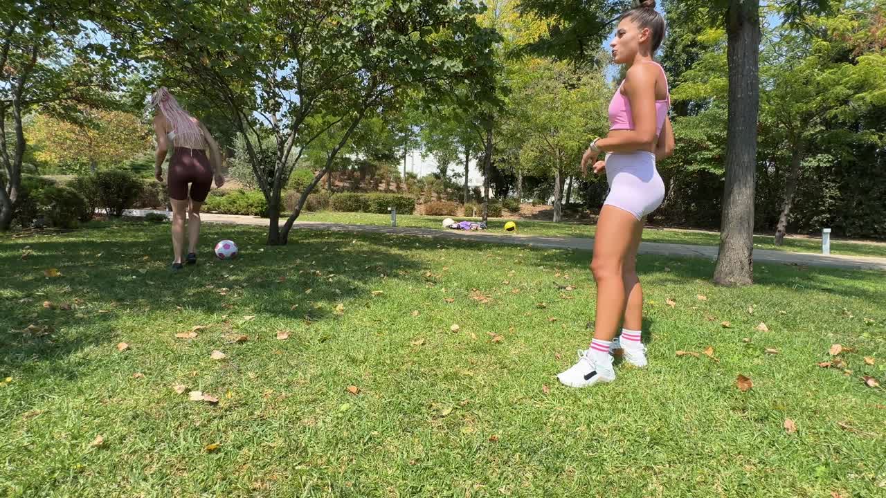 Two women playing soccer in the park